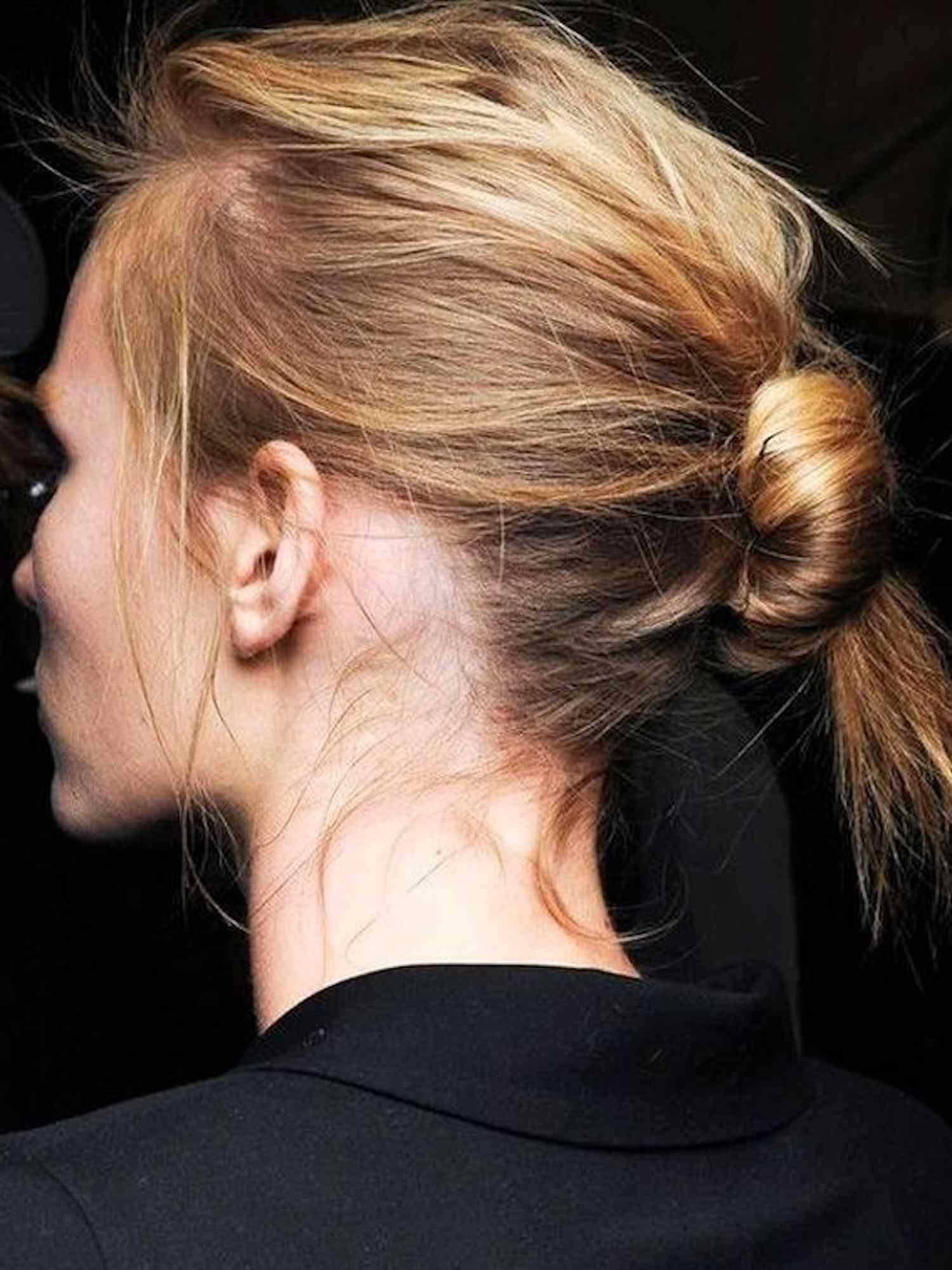 Back view of woman with blonde and ginger hair in tousled center bun hairstyle