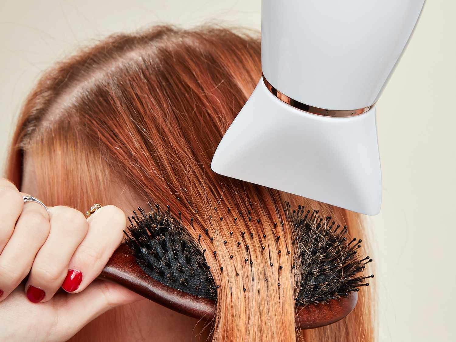 Close up of a woman brushing her red hair as she blow dries it